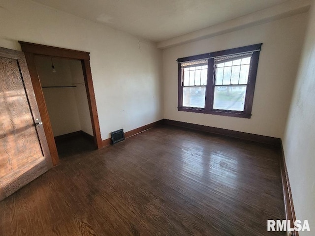 unfurnished bedroom featuring baseboards, visible vents, and dark wood-style floors