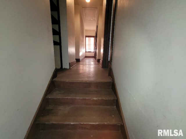 staircase featuring attic access, baseboards, and wood finished floors