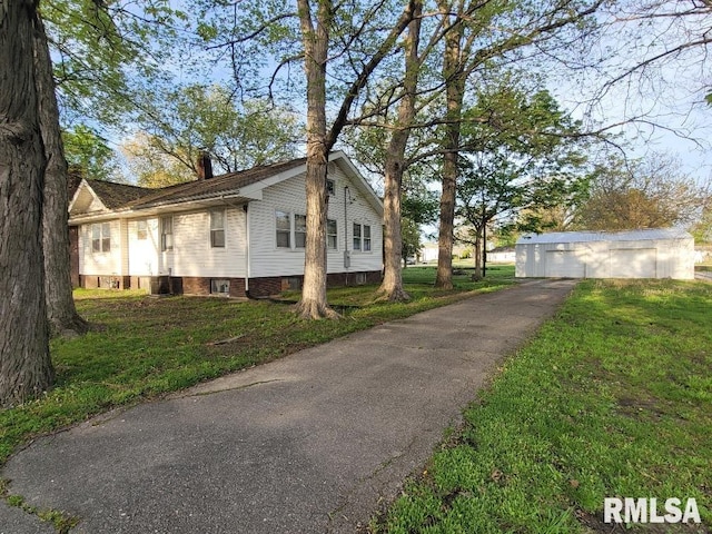 view of side of home with a chimney, aphalt driveway, a yard, and a garage