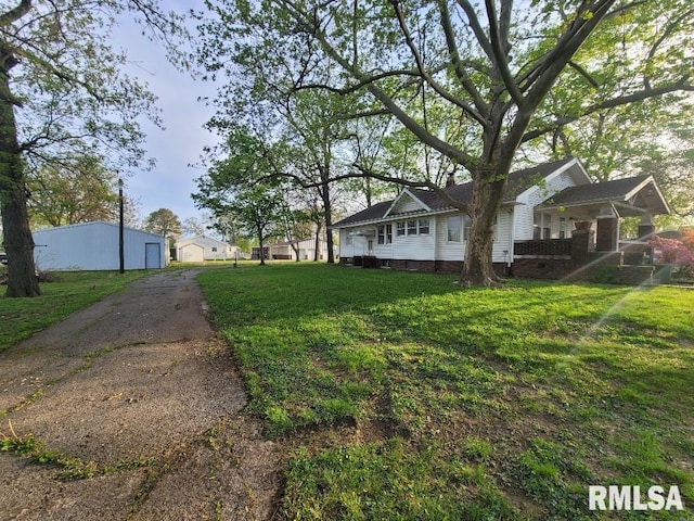 exterior space with a yard, an outbuilding, and aphalt driveway