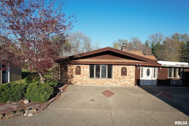 single story home with a chimney and brick siding