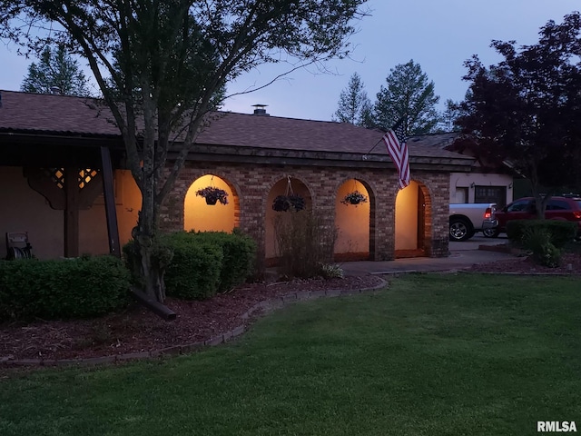 view of front facade with a garage, brick siding, a front lawn, and roof with shingles