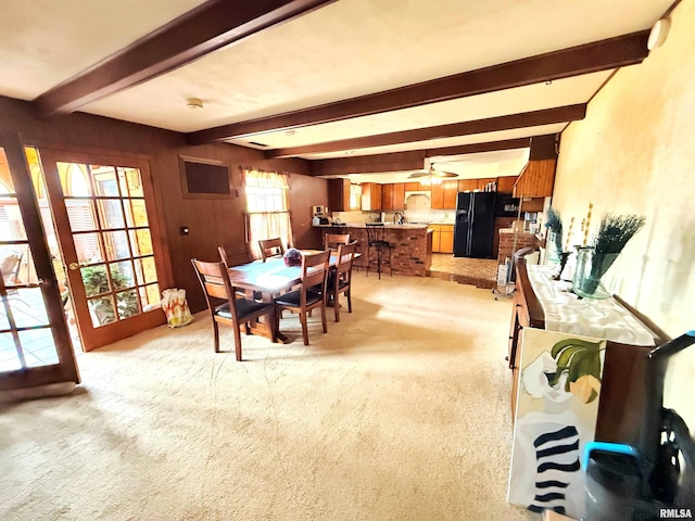dining area with beam ceiling, a ceiling fan, and light carpet