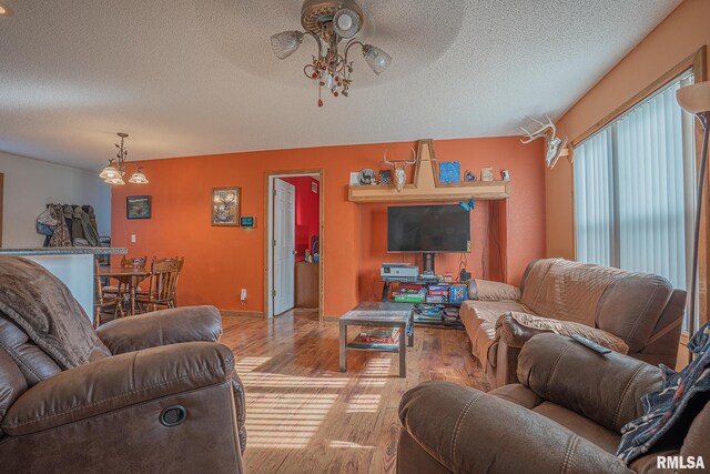 living room featuring a textured ceiling, ceiling fan, light wood finished floors, and baseboards
