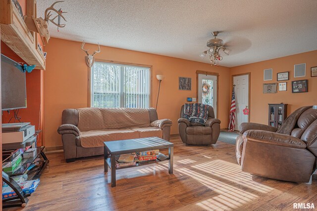 living room with a textured ceiling, ceiling fan, and wood finished floors