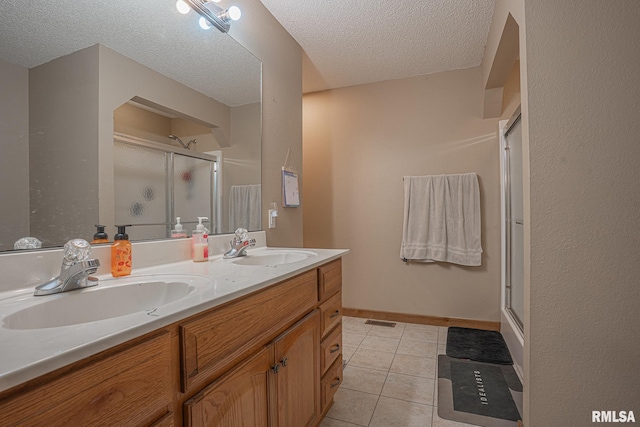 bathroom featuring tile patterned floors, a shower stall, double vanity, and a sink