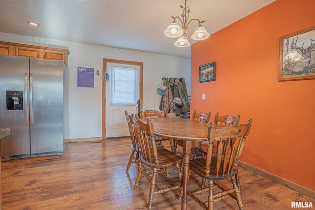 dining room featuring wood finished floors, a chandelier, and baseboards