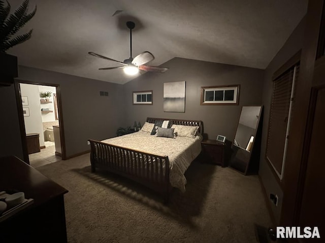 carpeted bedroom featuring lofted ceiling, ceiling fan, visible vents, baseboards, and ensuite bath