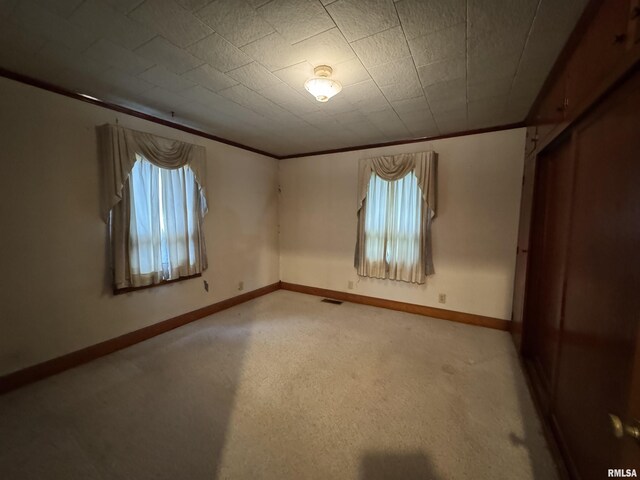 unfurnished room with ornamental molding, visible vents, and light colored carpet