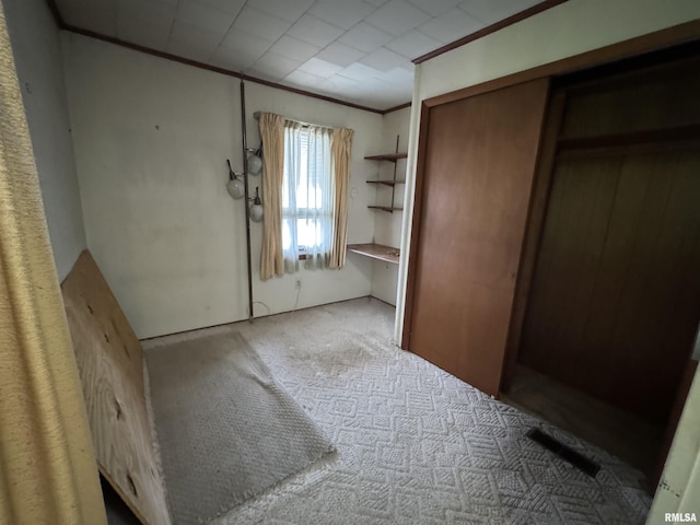unfurnished bedroom featuring carpet, ornamental molding, and a closet