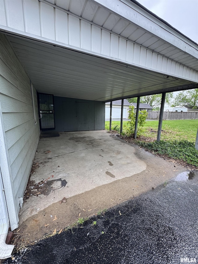 view of parking with a carport and fence
