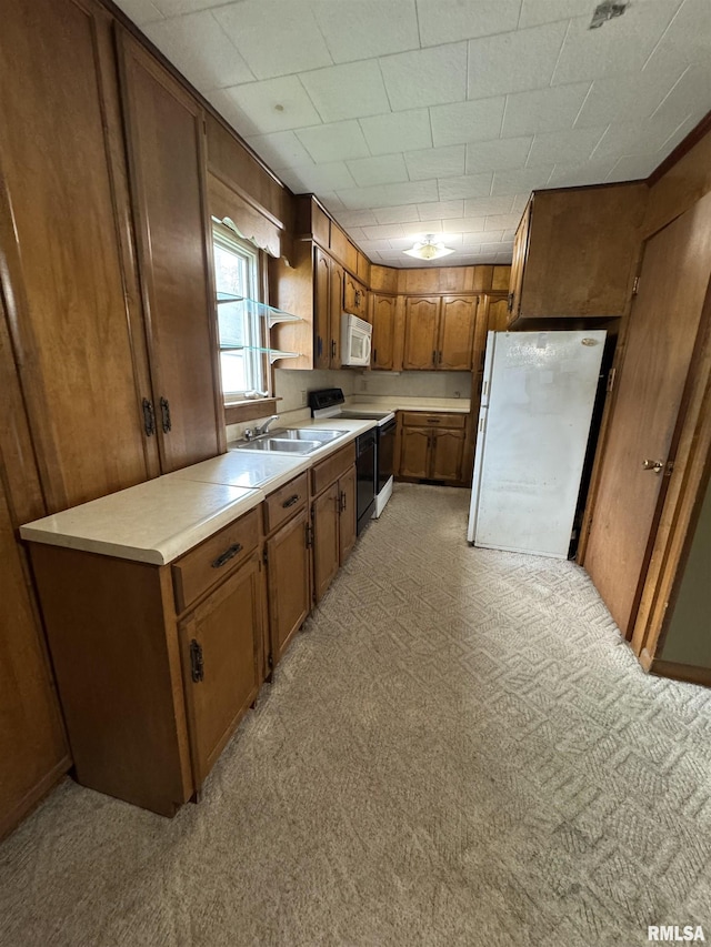 kitchen with brown cabinets, white appliances, light countertops, and a sink