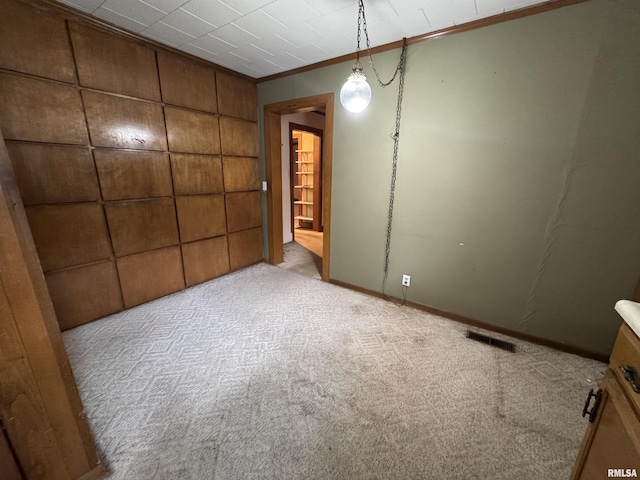 empty room with ornamental molding, visible vents, and carpet