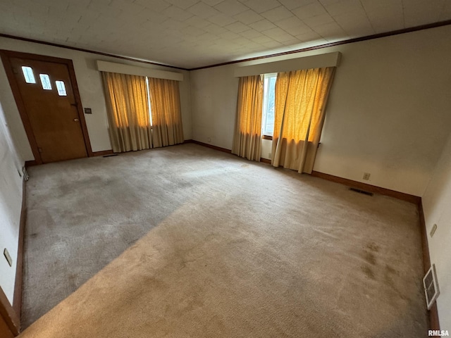 carpeted spare room featuring visible vents, ornamental molding, and baseboards