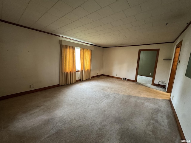 carpeted spare room featuring visible vents, crown molding, and baseboards