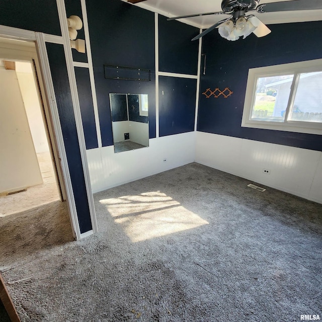 carpeted empty room with visible vents and a ceiling fan