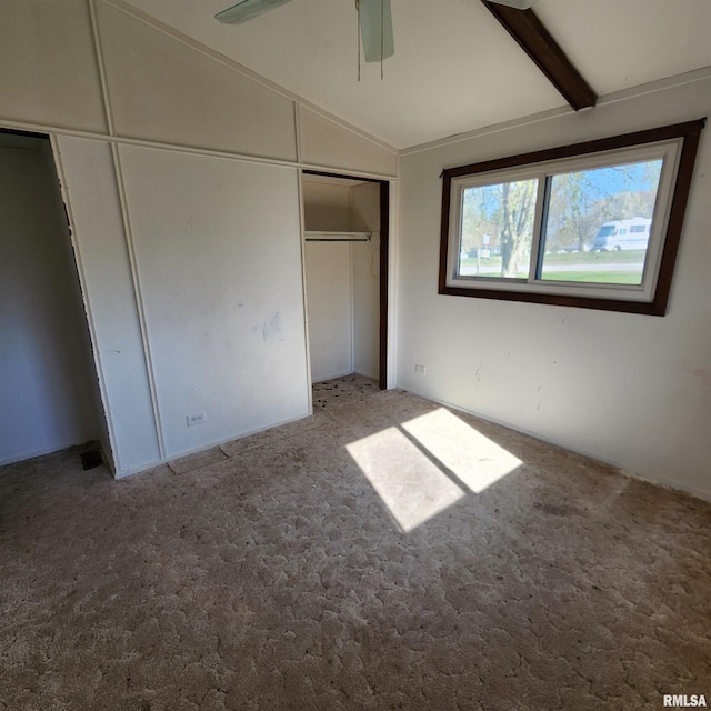unfurnished bedroom with lofted ceiling with beams, ceiling fan, a closet, and carpet flooring