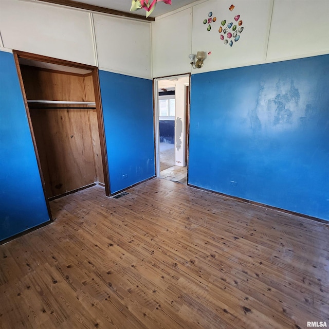 unfurnished bedroom featuring a closet, visible vents, and wood finished floors