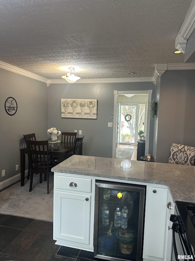 kitchen with beverage cooler, ornamental molding, white cabinets, and black gas range oven