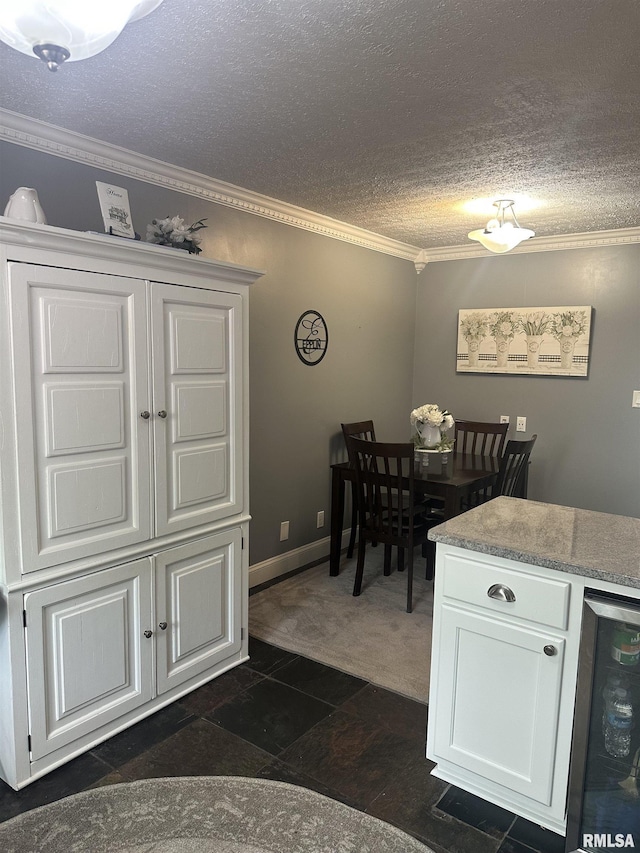 dining space with ornamental molding, wine cooler, a textured ceiling, and stone finish flooring