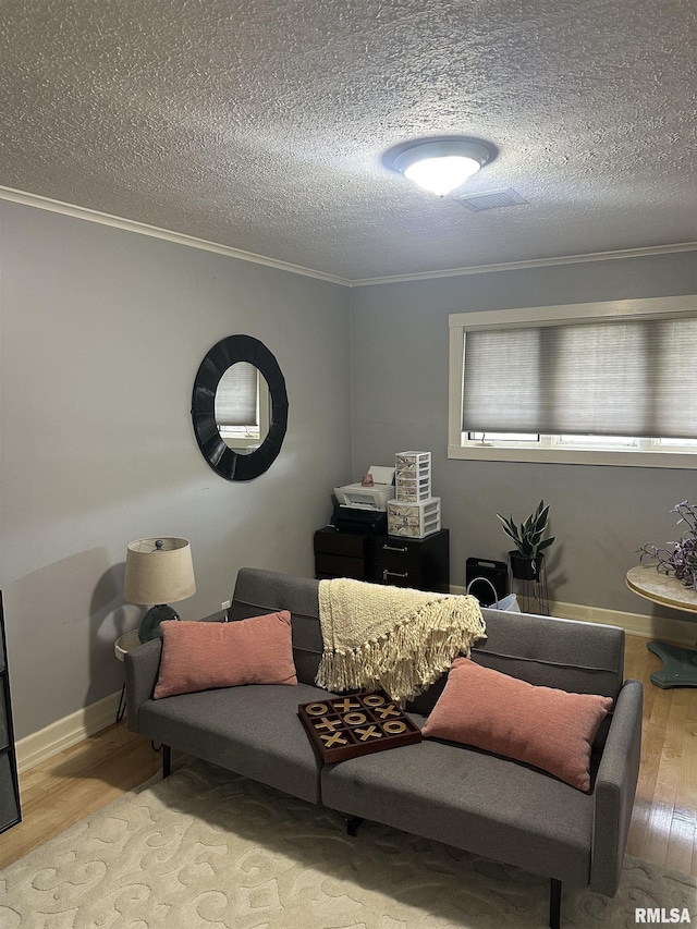sitting room with a textured ceiling, wood finished floors, crown molding, and baseboards