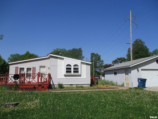 rear view of house featuring a lawn, a detached garage, a deck, and crawl space