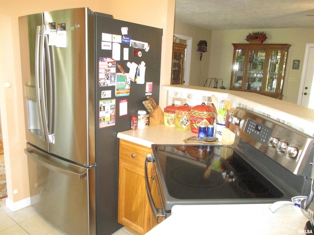 1607 Marion St, Carterville, IL 62918 - kitchen featuring stainless steel appliances, light countertops, light tile patterned flooring, and brown cabinets