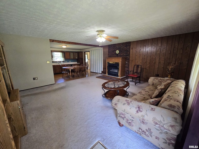 living room with a ceiling fan, a textured ceiling, wood walls, and a fireplace