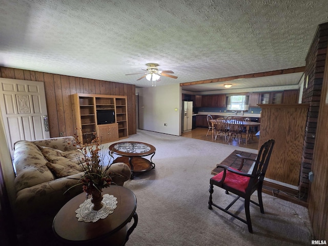 living room with light colored carpet, a textured ceiling, ceiling fan, and wooden walls