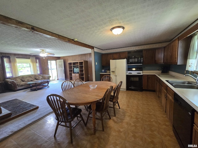 dining space featuring a ceiling fan, wood walls, and a textured ceiling