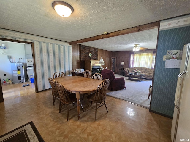 dining area with a textured ceiling, wallpapered walls, light floors, and electric water heater