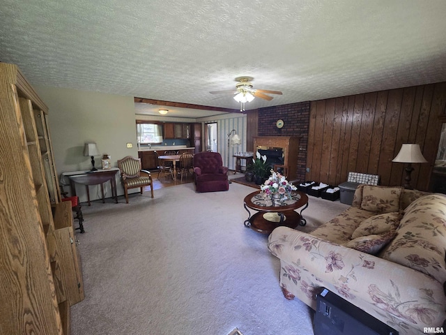 living room featuring ceiling fan, a brick fireplace, carpet flooring, and a textured ceiling