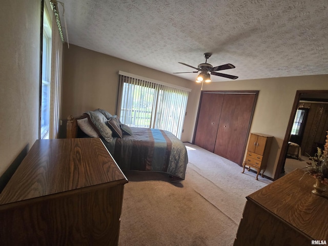 carpeted bedroom with ceiling fan, a closet, and a textured ceiling