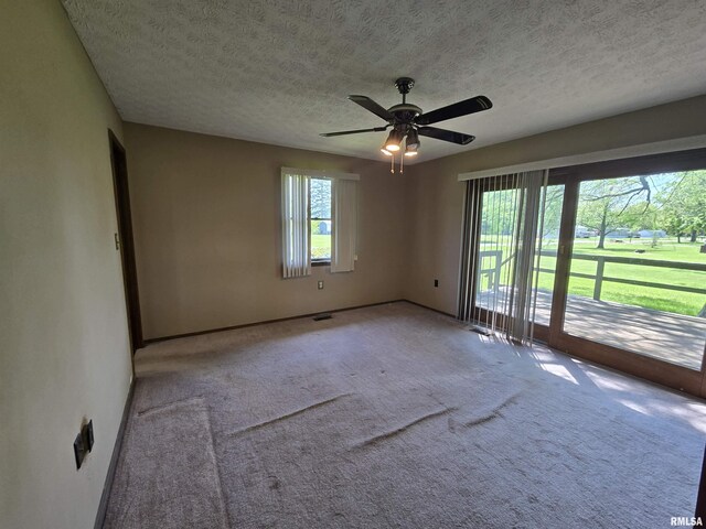 carpeted spare room featuring baseboards, a textured ceiling, ceiling fan, and visible vents