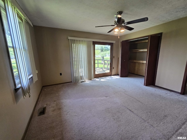 interior space featuring carpet flooring, baseboards, visible vents, and multiple windows
