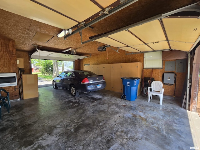 garage with a garage door opener, heating unit, and electric panel