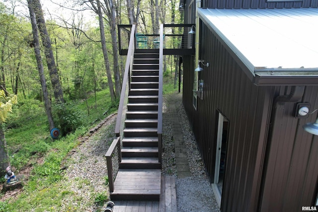 view of home's exterior featuring a deck, stairs, and a wooded view