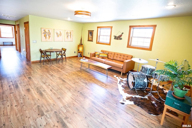 living room featuring wood finished floors, a healthy amount of sunlight, visible vents, and baseboards
