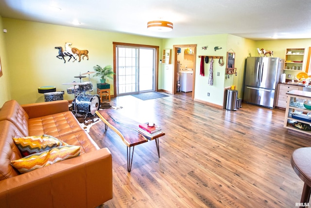 living area with wood finished floors, washer / dryer, and baseboards