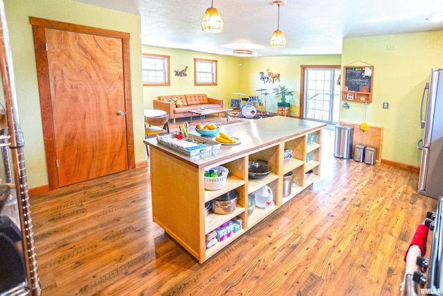 kitchen featuring open shelves, a wealth of natural light, decorative light fixtures, light wood-style flooring, and freestanding refrigerator