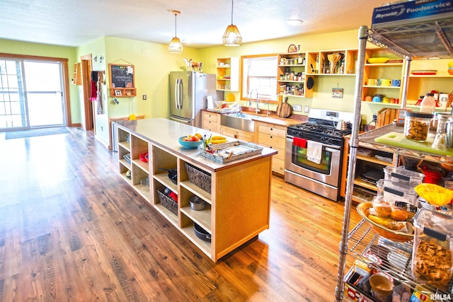 kitchen featuring appliances with stainless steel finishes, light wood-style floors, open shelves, and a sink