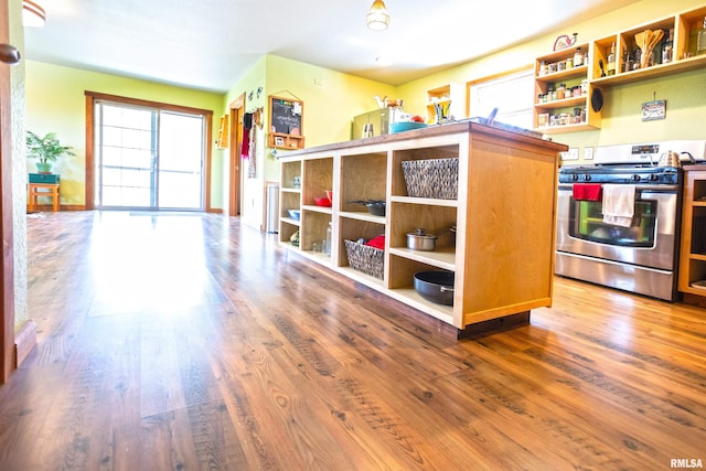 kitchen featuring stainless steel gas range, open shelves, and wood finished floors