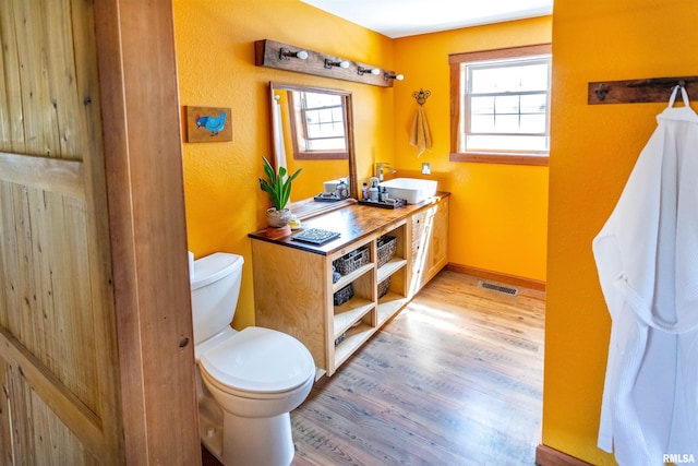 bathroom with wood finished floors, visible vents, toilet, and a healthy amount of sunlight