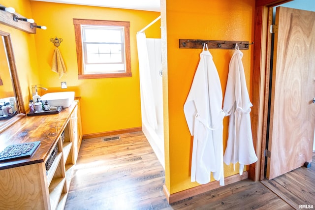 bathroom with curtained shower, visible vents, baseboards, wood finished floors, and vanity