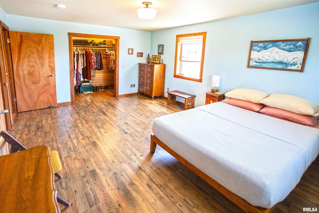 bedroom featuring a spacious closet, wood finished floors, and a closet