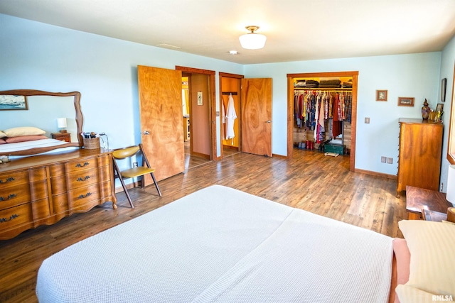 bedroom with wood finished floors, a closet, baseboards, and a walk in closet