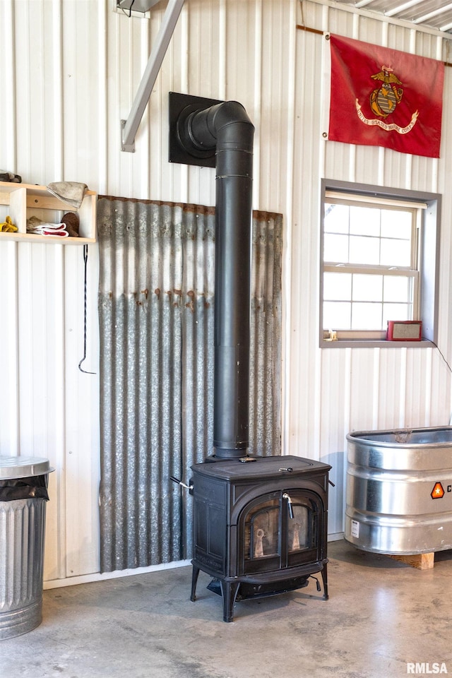 room details with finished concrete flooring, wood walls, and a wood stove