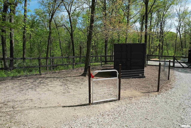 view of community featuring fence and a wooded view