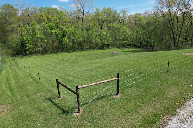 view of yard with a wooded view and fence