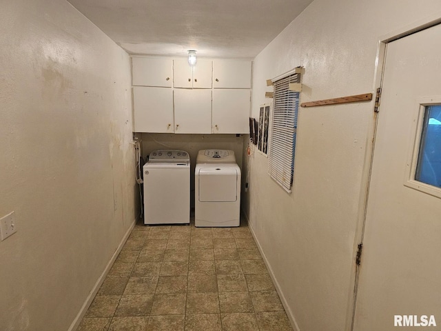 laundry area with baseboards, stone finish flooring, cabinet space, and washing machine and dryer